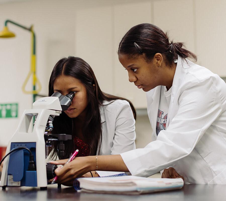 biology and health science students in a laboratory looking into a microscope